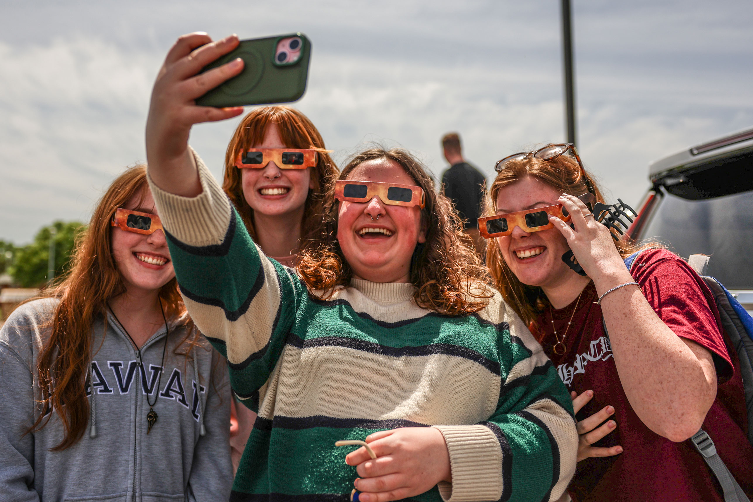 A group of OSUIT students wearing solar glasses, smiling, and taking a selfie during the 2024 total solar eclipse in Oklahoma.