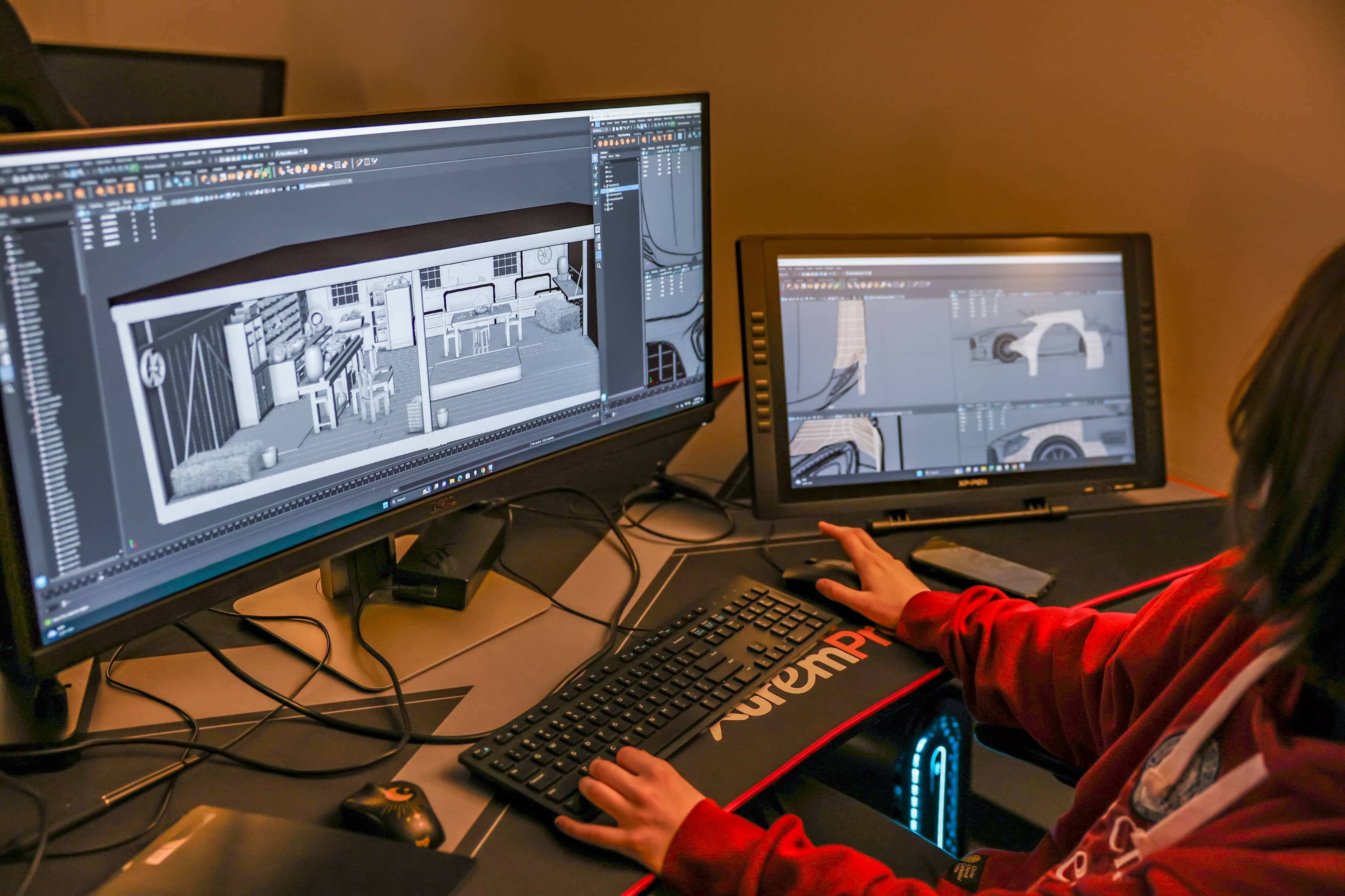 A student at OSUIT using dual monitors to work on a detailed 3D modeling project, showcasing their proficiency in digital animation and design.